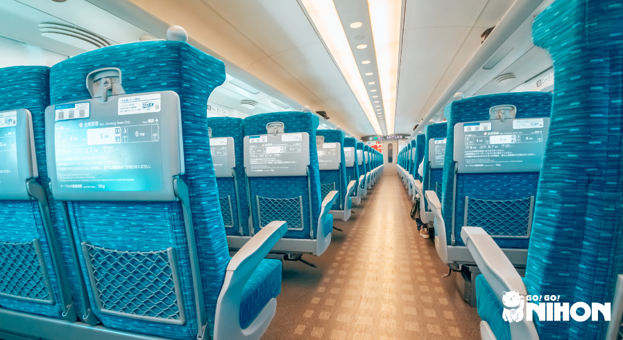 Interior de un vagón Shinkansen con filas de asientos azules