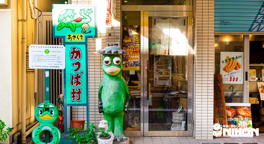 Kappa-staty framför en butik med fler kappa-bilder i Kappabashi.