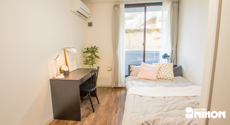Bed, desk, and AC unit in share house room