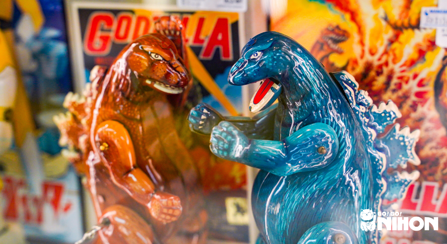 En brun Godzilla-figur brevid en blå Godzilla-figur