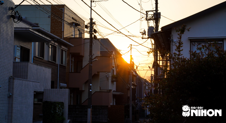 residential street with houses and apartment buildings with a sunset behind them