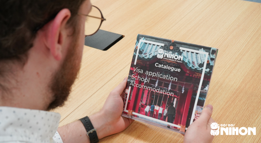 Person holding a Go! Go! Nihon visa application School Accommodation catalogue.