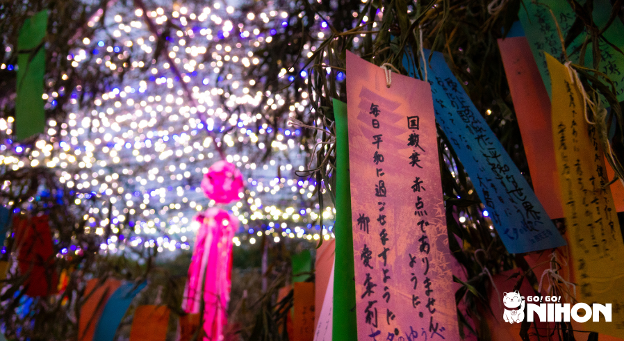 tanabata decorations hanging from tree with lights and streamers in background