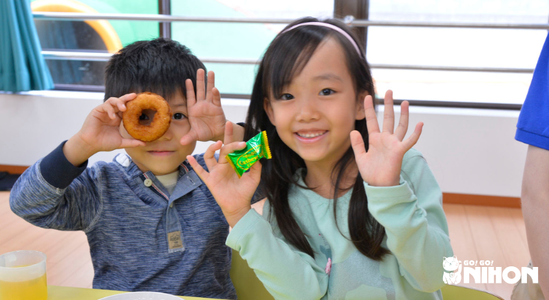two children waving and holding snacks