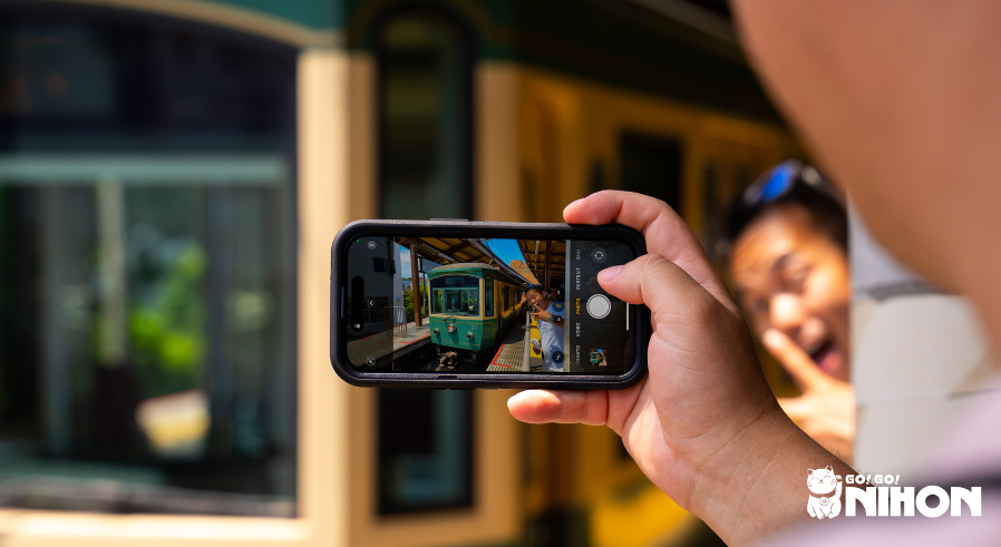 Eine Person macht mit dem Smartphone während eines Study Trips ein Foto von einem Zug und einer anderen Person