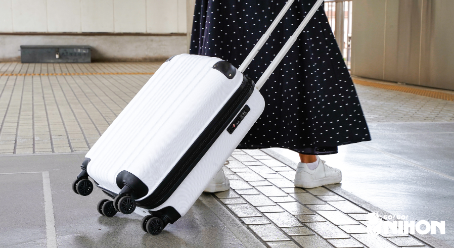 woman rolling a white suitcase in a train station