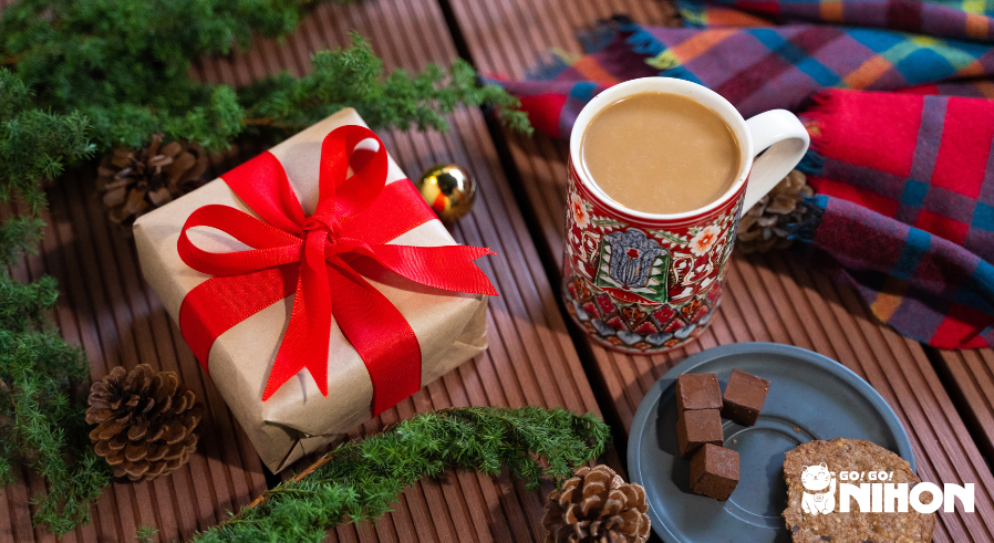 Flat lay of a Christmas present, cup of hot coco, and plate of chocolate and a cookie