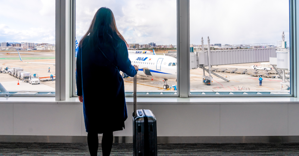 woman at airport with suitcase looking at planes