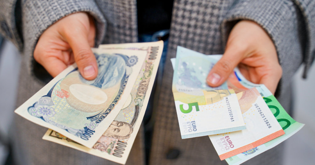 hands holding yen and euro bills