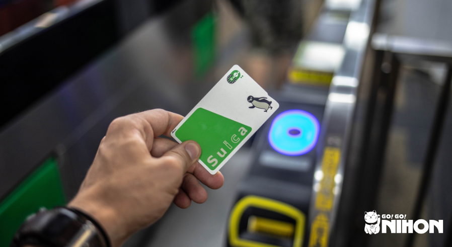 person holding a suica card in front of a ticket gate