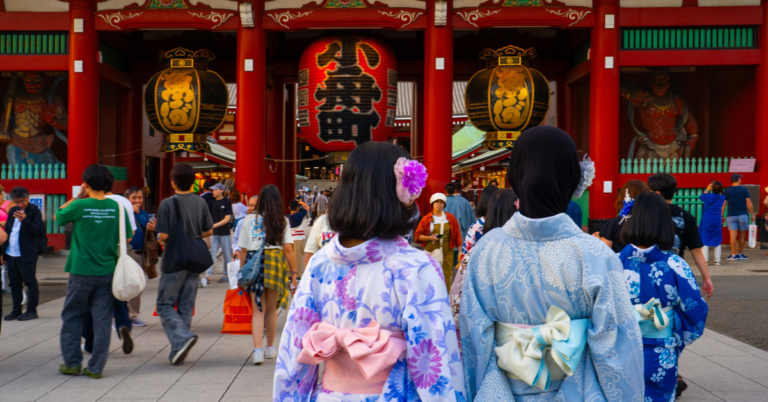 Two women in traditional kimono pose at a Japanese shrine during their cultural study trip.