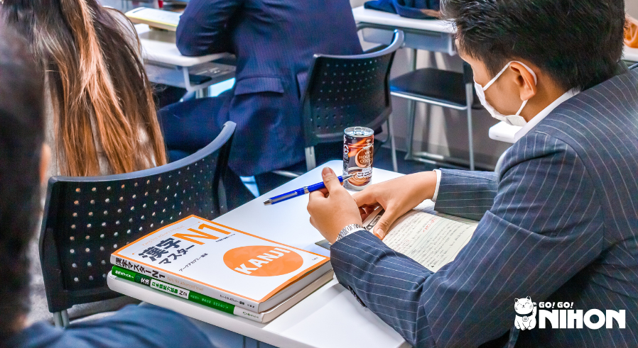 Student in class at a language school studying for the JLPT with N1 and N2 textbooks on desk