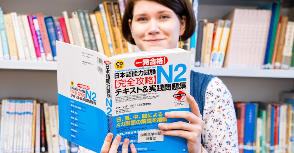 woman holding up an N2 textbook