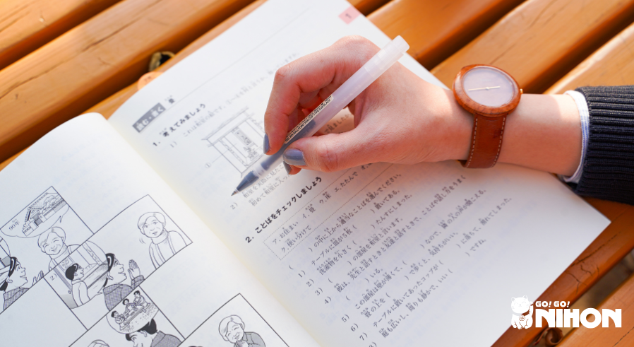 Persona che studia per un esame di lingua giapponese, usando un libro di testo giapponese.