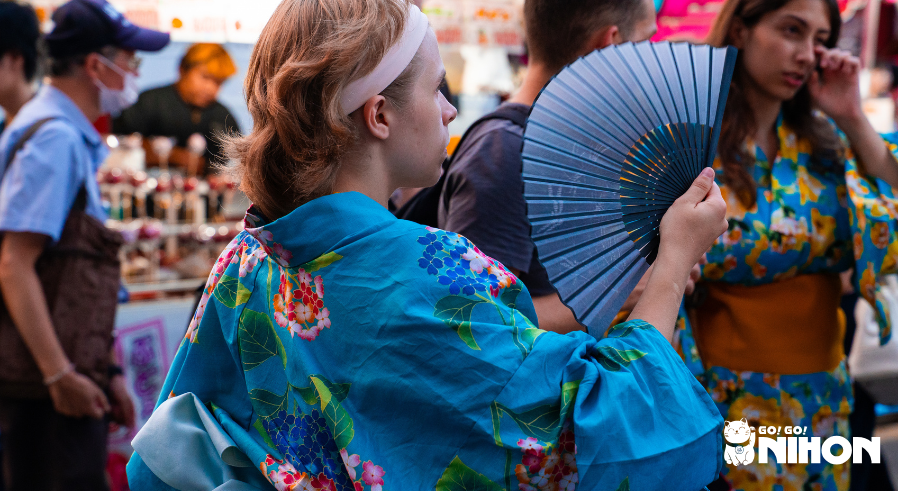 Woman wearing a blue yukata with a blue fan at a matsuri