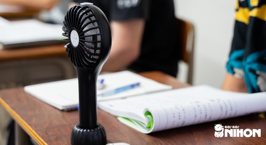 A standing portable fan on a desk