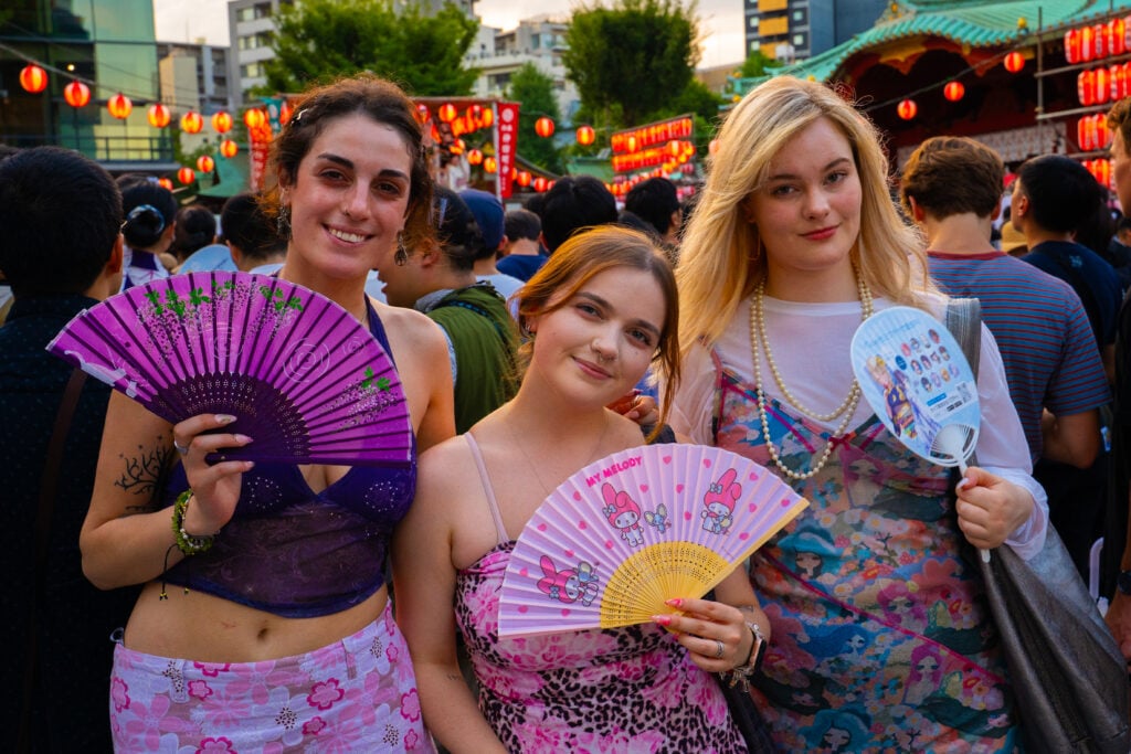 3 students holding a Japanese fan at a traditional festival